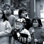 Balck and white photo fo boys and grils stanidng on the street with hockey sticks