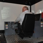 Dean, Dr. Norman Halden at the ThoroughTec Cybermine underground mining simulator operating a load-haul-dumper at the Northern Manitoba Mining Academy. Photo Credits: Rob Penner.