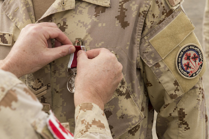 Colonel Shayne Elder, Commander of Air Task Force – Iraq, places the General Service Medal on the chest of an Operation IMPACT Roto 1 member, during a parade in front of Camp Patrice Vincent, in Kuwait on December 12, 2015. Photo: OP IMPACT, DND KW02-2015-0399-013 ~ Le colonel Shayne Elder, commandant de la Force opérationnelle aérienne en Irak, épingle la Médaille du service général sur la poitrine d’un membre de la Roto 1 de l’opération IMPACT lors d’un défilé devant le Camp Patrice Vincent, au Koweït, le 12 décembre 2015. Photo : OP IMPACT, MDN KW02-2015-0399-013