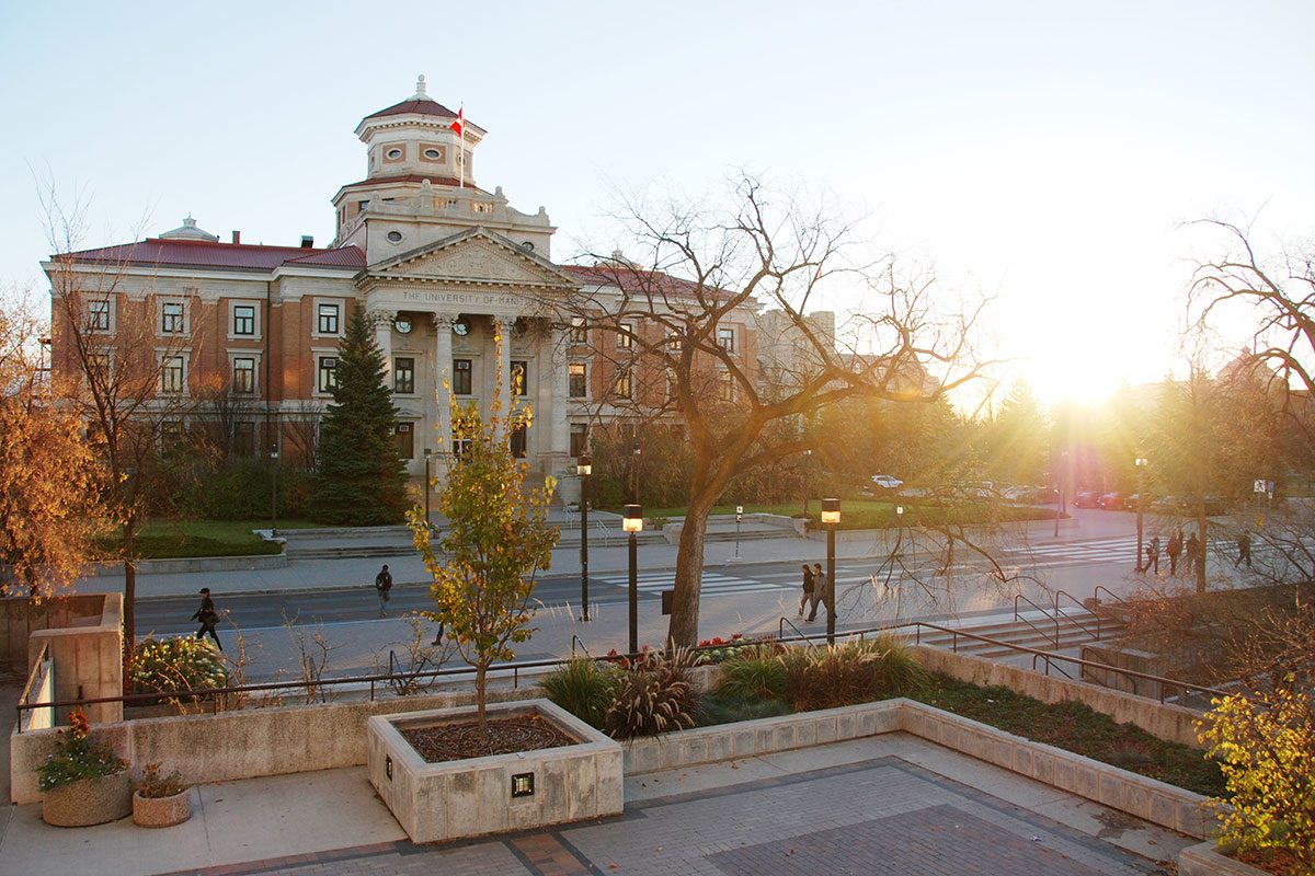 University of Manitoba administration building, with the sun rising behind it in autumn.