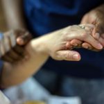 Hands being held in bedside health care.