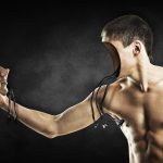 an android has town off its face and looks at it with contemplation