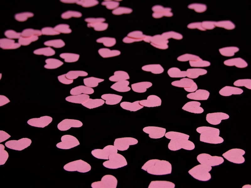 pink paper hearts cut out and laying on black cloth
