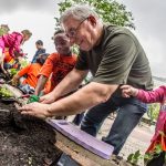 President and Vice-Chancellor David Barnard planting with students from École St. Avila at the 2016 Campus Beautification Day