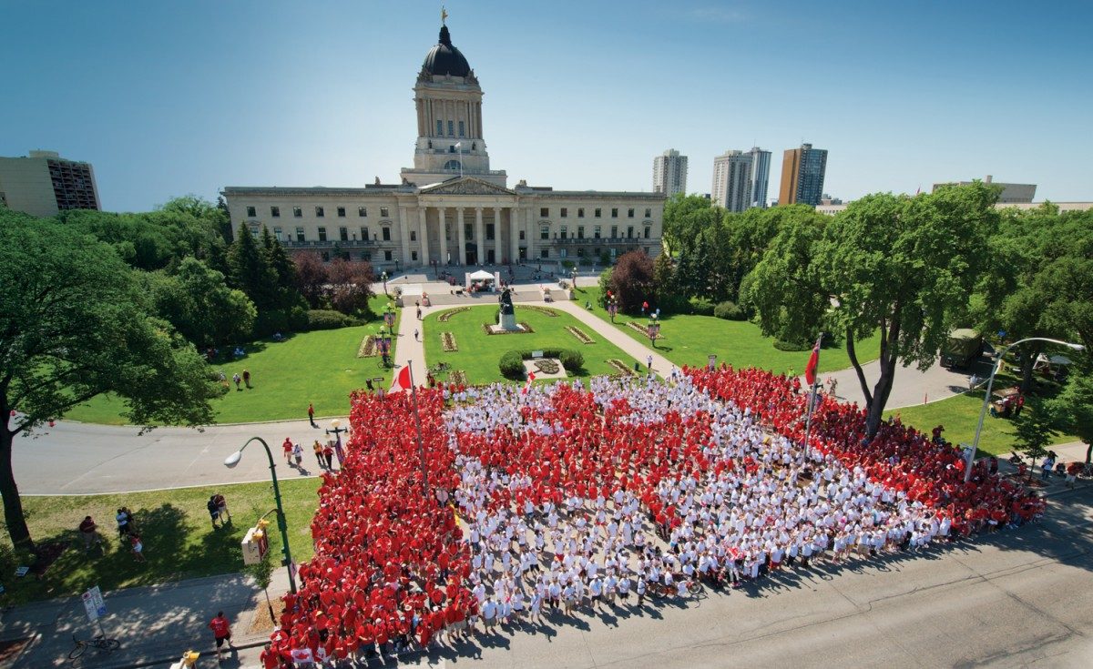 Canada Flag in front of the Manitoba legislature made up of people.