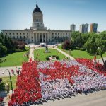 Canada Flag in front of the Manitoba legislature made up of people.