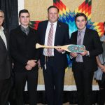 A group of people hold a painted paddle