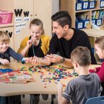 Gaston Lopez Ficher sits with young students at a table