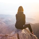 Woman looks at sky from a mountain top. // Image from Pixabay.