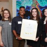 Students stand with the President in his house alongside the Dean