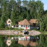 A cbin on teh the lake shore, surrounded by trees