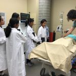 Students and a doctor do an exercise with a manikin