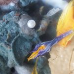 a photo of rotting food with a wilted flower and pearl laying atop the moldy mass