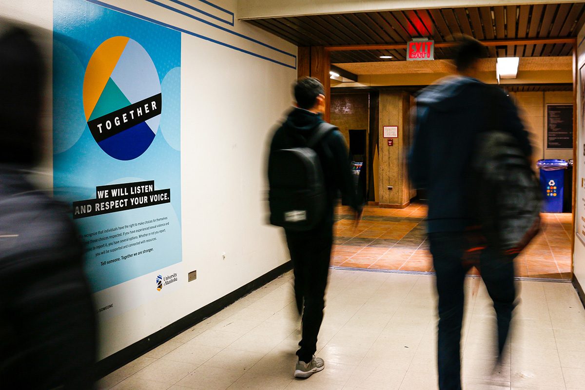 students walk by a Sexual Violence Awareness campaign poster