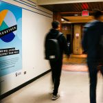 students walk by a Sexual Violence Awareness campaign poster