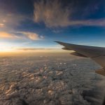 Looking out over clouds and the wing of an airplane in flight. // Image from Pixabay