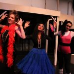 Three female performers with arms raised from the play Macbeth