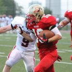 A football player running with the football trying to break a tackle