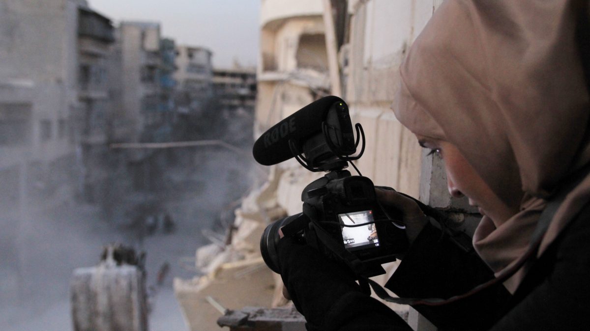 Syrian woman filming a street filled with war activities