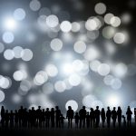 People stand in silhouette holding hands.