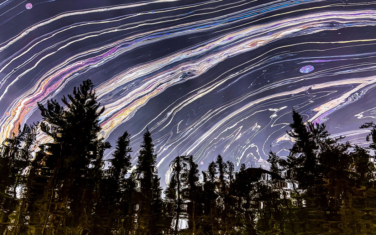 An oil slick on a test lake showing a reflection of a forest