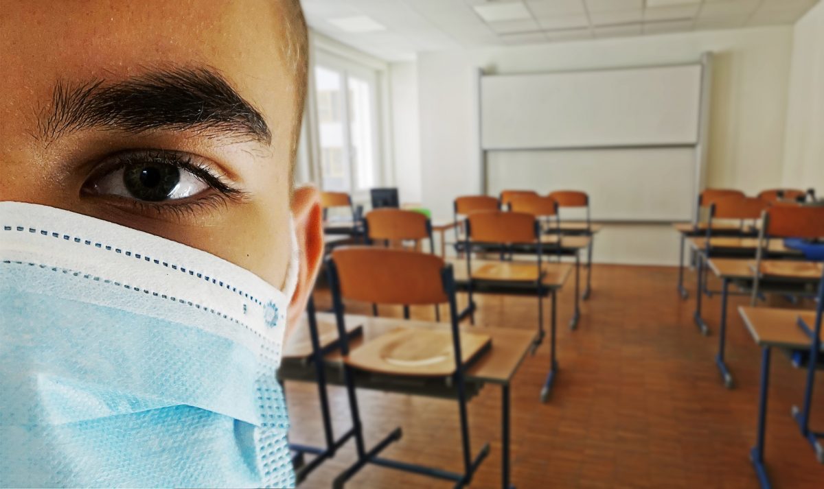 Close up of person wearing a mask in an empty classroom