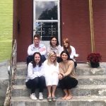 6 students sitting on the front steps of their home