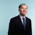 Yik Au standing in a suit.