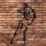 Protest fist art on brick wall.