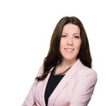 Picture of a woman smiling with her arms crossed. She is wearing a pink blazer and black shirt.