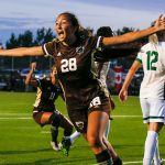 Bison women's soccer player celebrates with extended arms on the field