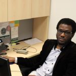 Stephen Alalade sitting at a computer desk.