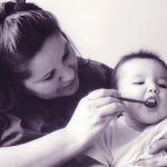 An Indigenous woman brushes her baby's teeth.
