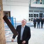 Doug Ruth smiles as he reveals a sign. The sign says "Doug Ruth Laneway"