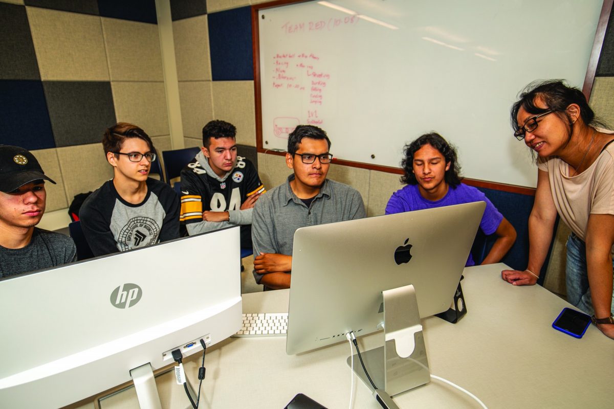 Group of students huddled around two computers.