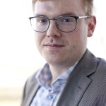 Headshot of Brandon Trask, red hair, glasses, slight smile.