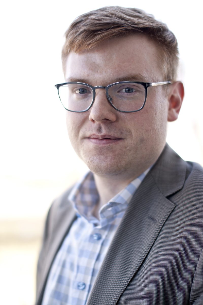 Headshot of Brandon Trask, red hair, glasses, slight smile.