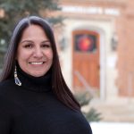 Stephanie Scott stands outside and the National Centre for Truth and Reconciliation is in the background.