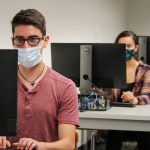 Students wearing masks work on computers