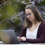 A student works on a laptop on the UM campus