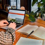 A person with a plaid shirt views the UM website on a laptop