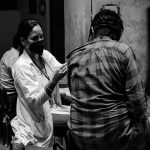 A woman in a lab coat administers a shot to a person. // Photo from Unsplash