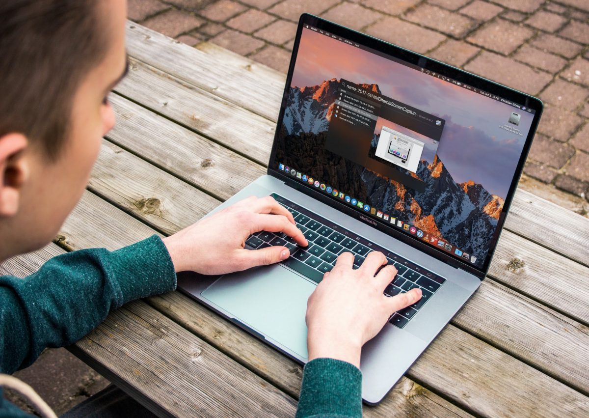 student in sweatshirt working on a laptop at a picnic bench