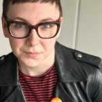 clodeup of woman wearing glasses, black leather jacket and pride pin