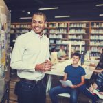 Man shares information on a bulletin board with students