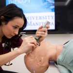 A respiratory therapy student practices her skills on a manikin..
