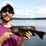 Phil Grayson, holding a fish with a lake in the background