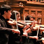 music student playing violin with ensemble