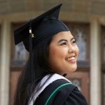 A smiling graduating student in cap and gown looks towards her future.