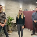 Young Friends of Engineering founding members Derek Neufeld, Katie Moist and Dan Nenadov stand socially distanced smiling and posing for the camera.